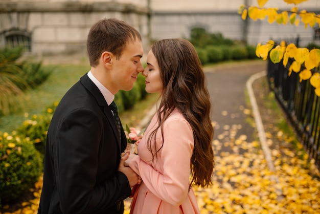 Happy young newly married wedding couple on walk in golden yellow fall autumn park near vintage atmosphere gothic cathedral.