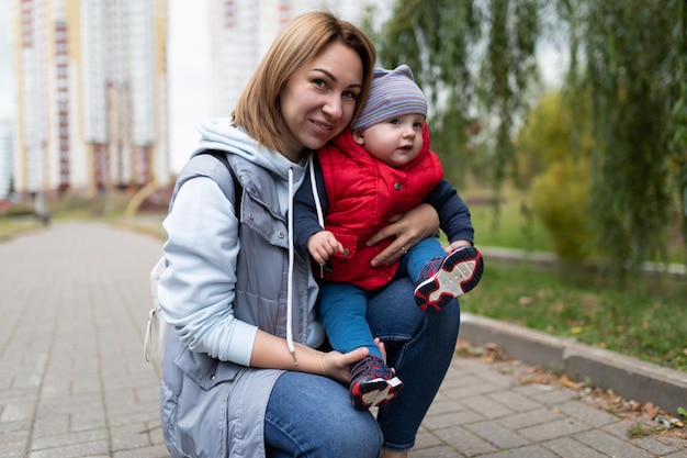 Happy young parent walking with her little son in the city park