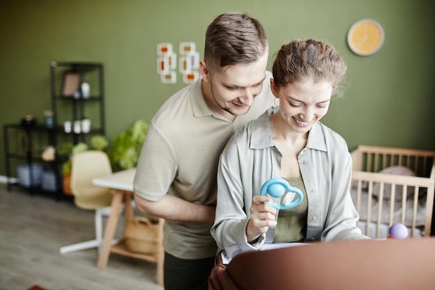 Happy young parents playing with their baby in cradle and enjoying parenthood together at home