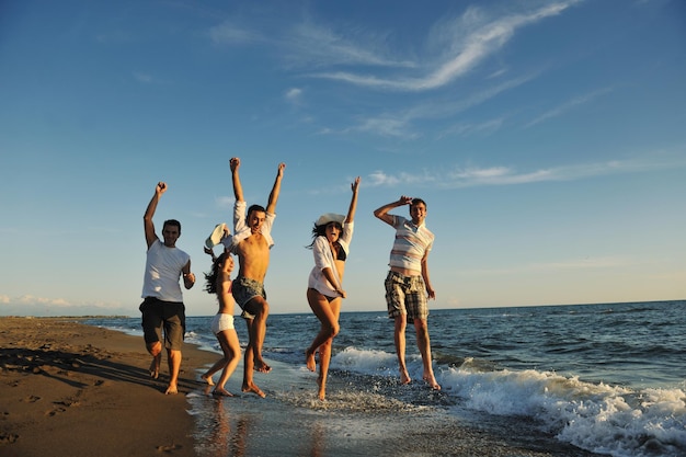 happy young people group have fun white running and jumping on beacz at sunset time