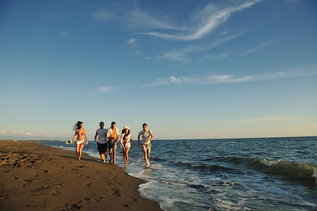 happy young people group have fun white running and jumping on beacz at sunset time