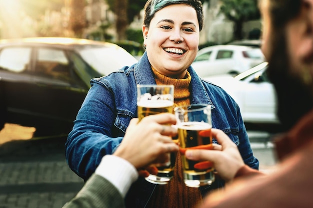 Happy young people at happy hour toasting beer glasses and having fun bonding group of best friends carefree ad urban outdoor pub people alcohol and togetherness life style concept