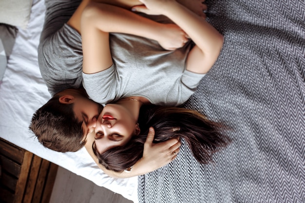 Happy young pregnant couple in bedroom at home