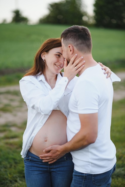 Happy and young pregnant couple hugging in nature