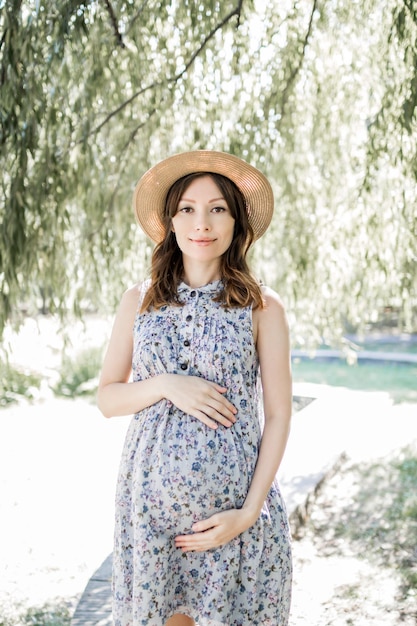 Happy young pregnant woman in the park on a spring or summer day.