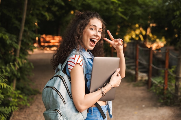 Happy young pretty woman holding laptop