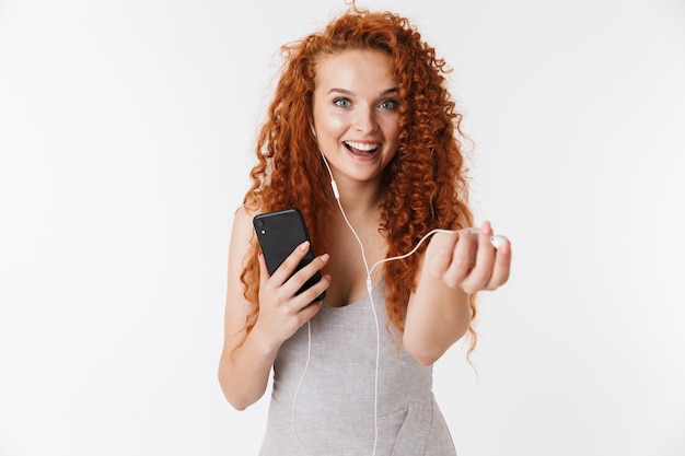 happy young redhead curly woman using mobile phone listening music.