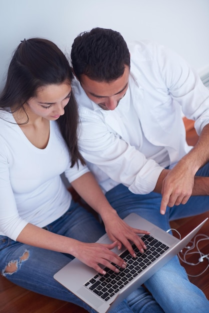 happy young relaxed  couple working on laptop computer at modern home interior