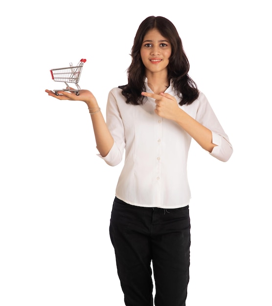 Happy young Smiling girl with a miniature trolley shopping cart on a white background Beautiful girl in shopping concept