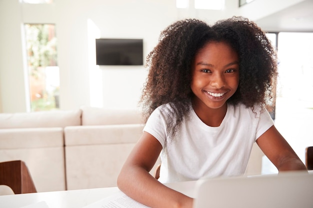 Happy young teenage black girl using laptop computer at home close up