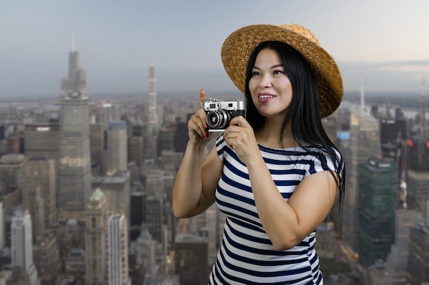 Happy young tourist korean woman aking a photo on vintage camera metropolis cityscape background