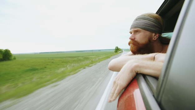 Happy young tourist man watching in car window relaxed while traveling