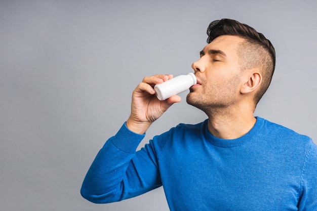 Happy Young ukrainian Handsome Man drinking probiotic Yogurt isolated over grey white Background Healthy lifestyle concept