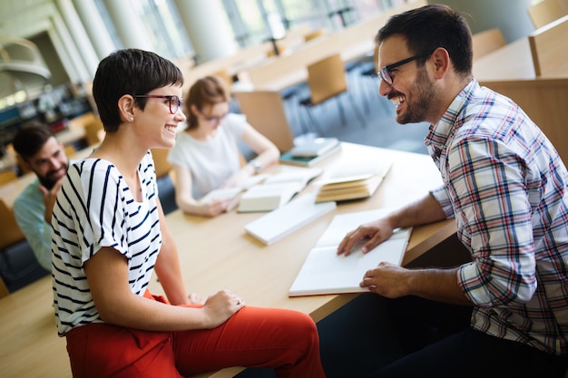 Happy young university students studying with books in library. Group of multiracial people in college library.