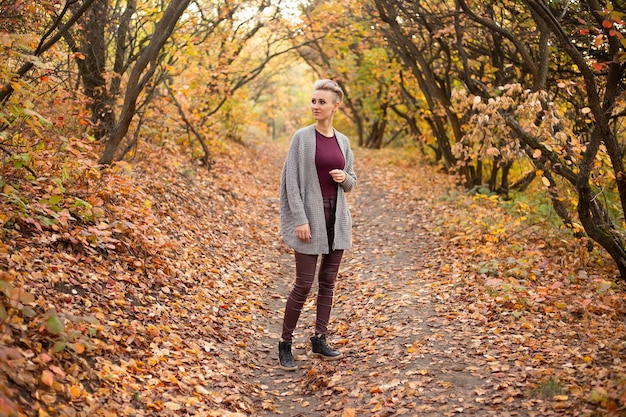 Happy young woman in autumn forest background with golden and red trees