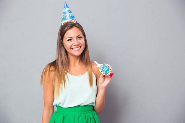 Happy young woman in birthday hat and whistle