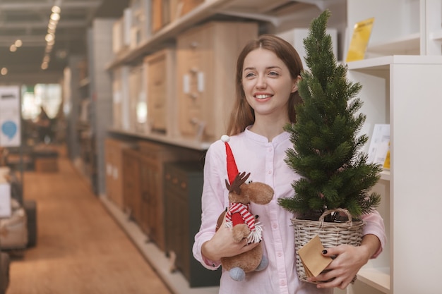 Happy young woman buying Christmas home decorations at furnishings store