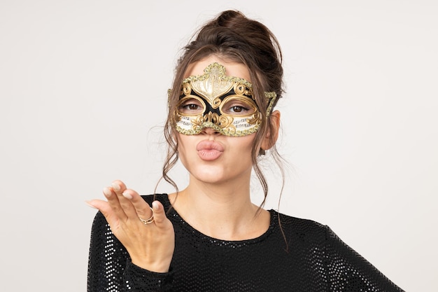 Happy young woman in dress and carnival mask on white background