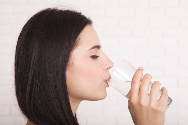 Happy young woman drinking water at home