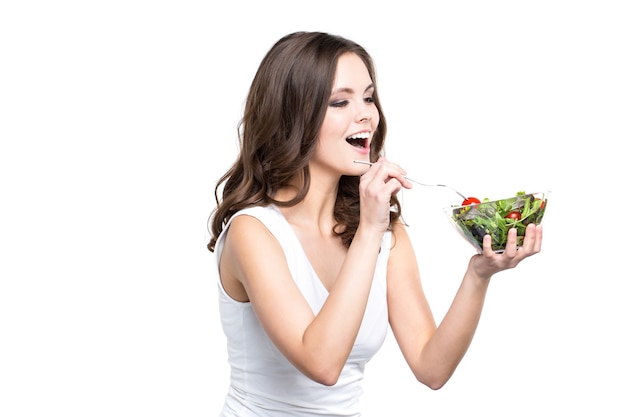 Happy young woman eating a fresh salad Isolated. Healthy lifestyle.