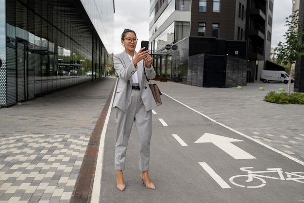 Happy young woman in elegant suit making selfie on the road