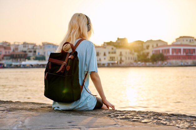 Happy young woman enjoying summer sunset vacation by the sea