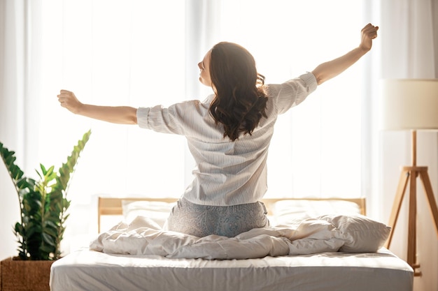 Happy young woman enjoying sunny morning on the bed.