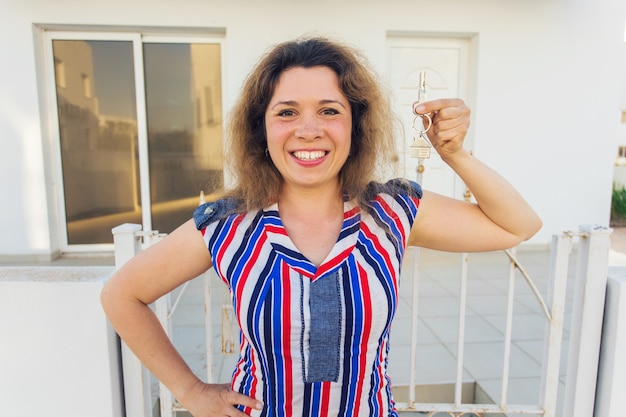 Happy young woman In Front of New Home with New House Keys