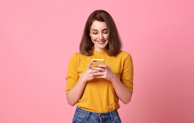 Happy young woman good looking using mobile phone isolated over pink space.