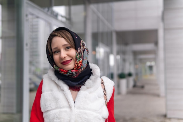 Happy young woman in headscarf in cold weather outdoors