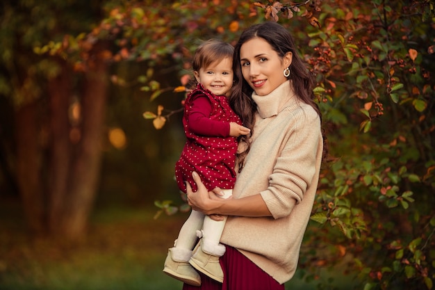 Happy young woman holds her little daughter in her arms