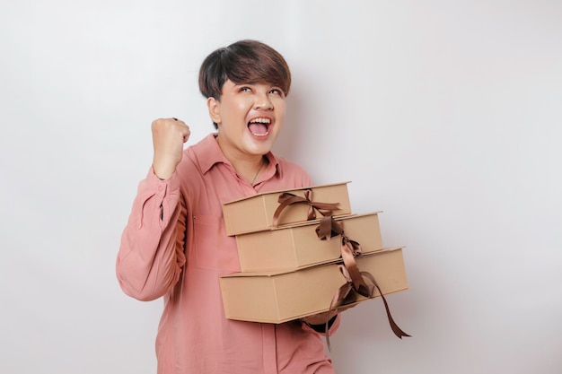 A happy young woman is wearing pink shirt and holding presents or shopping bag