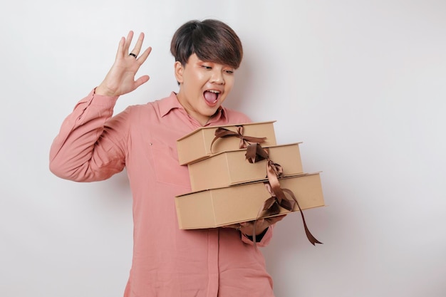 A happy young woman is wearing pink shirt and holding presents or shopping bag