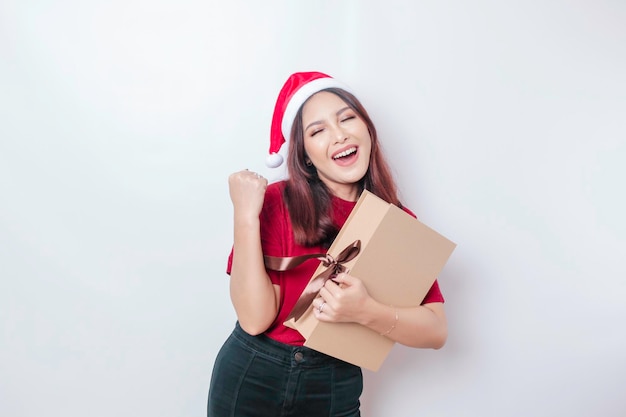 A happy young woman is wearing Santa Claus39 hat and holding Christmas presents