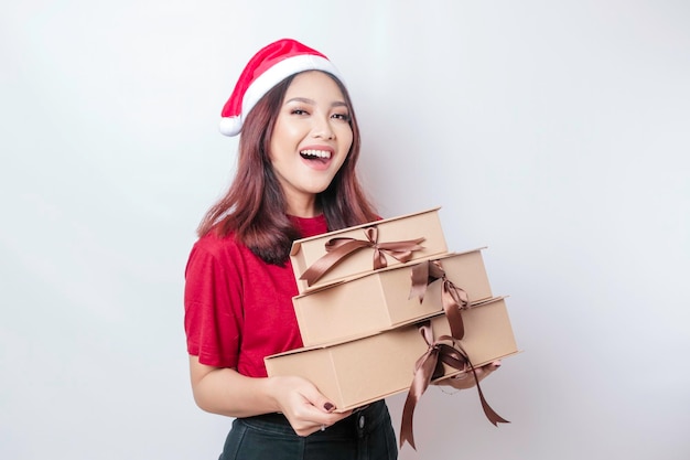 A happy young woman is wearing Santa Claus39 hat and holding Christmas presents