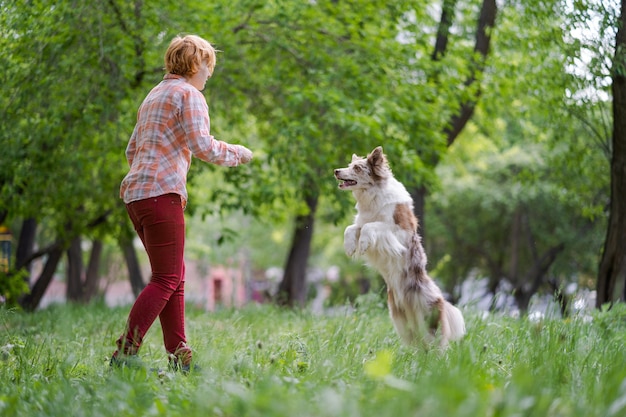 Happy young woman jogging with her dog in park.