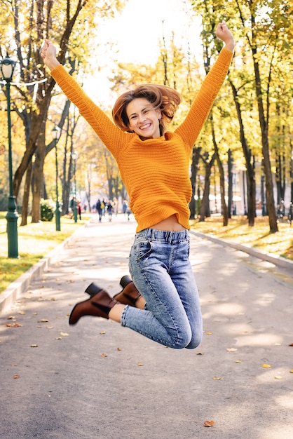 happy young woman jumping in autumn in the park