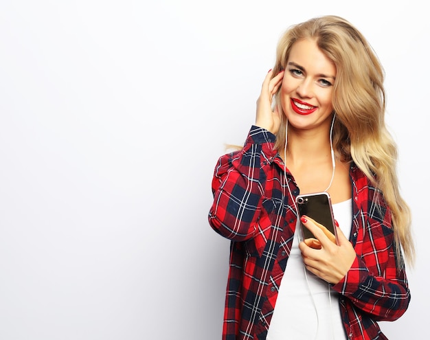 Happy young woman listening to music from smartphone over white