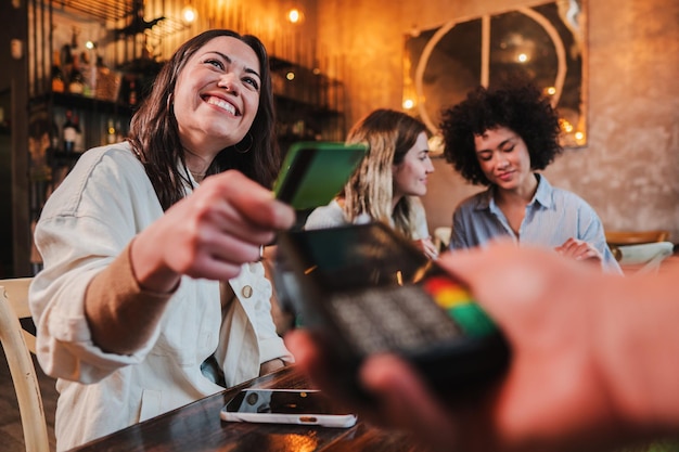 Happy young woman paying bill with a contactless credit card in a restaurant Female smiling holding a creditcard and giving a payment transaction to the cashier