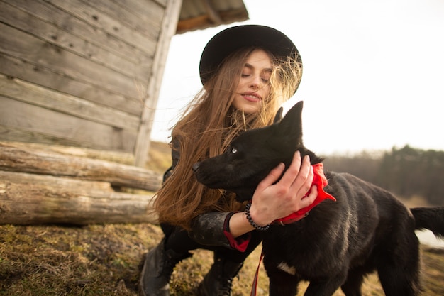 Happy young woman plaing with her black dog 