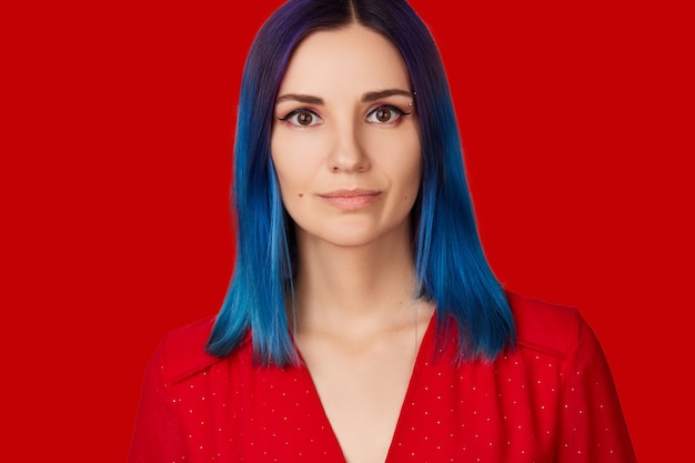 Happy young woman in red dress with blue hair on red background