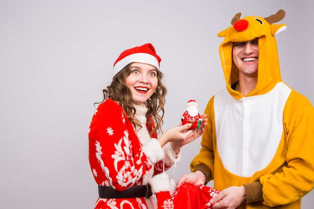 Happy young woman in santa claus hat and man in carnival costume of deer