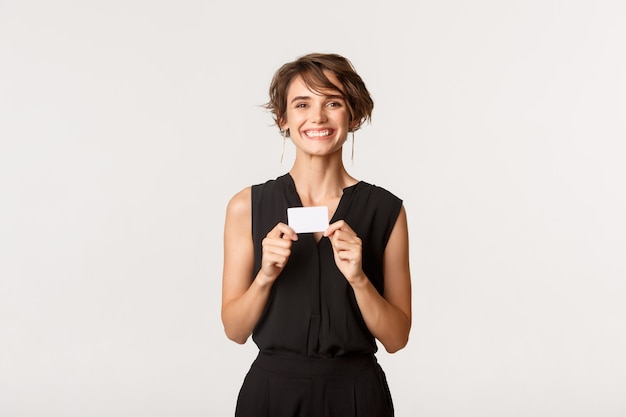 Happy young woman showing her credit card and smiling isolated