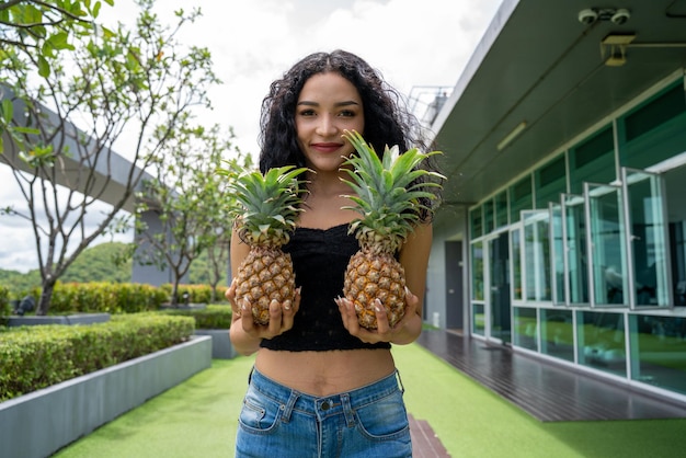 Happy young woman showing pineapple Pineapple fruit woman smiling healthy and joyful Mixedrace Asian Caucasian model with pineapple