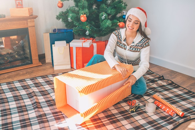 Happy young woman sitting on the floor and packs big boxes