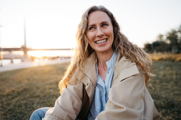 Happy young woman sitting on lawn outdoors in the city