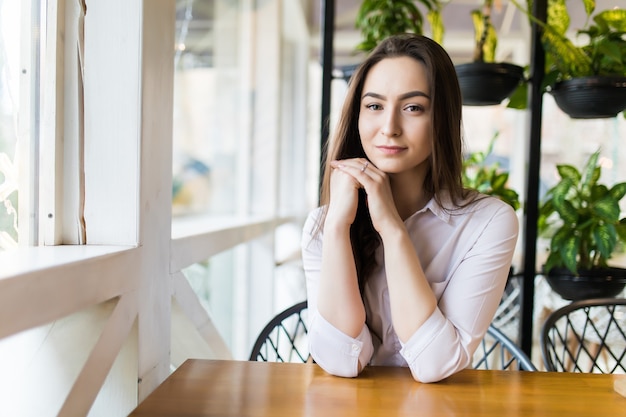 Happy young woman sitting and waiting for order in cafe