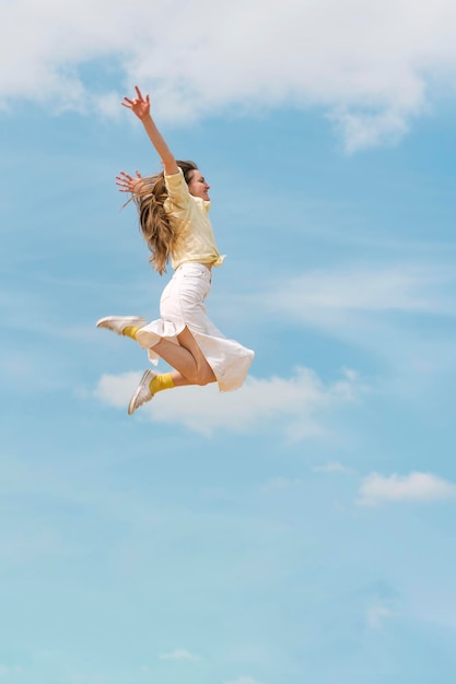 Happy young woman in the sky while jumping Floating in the air Side view of person