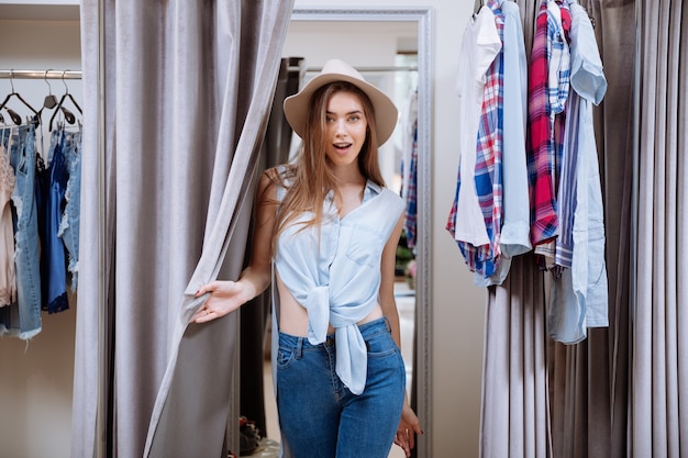 Happy young woman standing in fitting room in clothing store