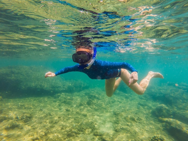 Happy young woman swimming underwater in the tropical ocean